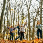 A family tossing autumn leaves in the woods